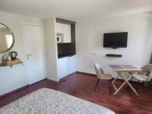 a room with a table and chairs and a television at Douglas in Colleville-sur-Mer