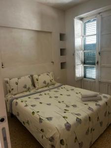 a bedroom with a bed with a floral bedspread and a window at Correri 125 in Modica
