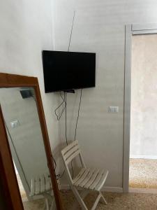 a room with a chair and a television on a wall at Correri 125 in Modica