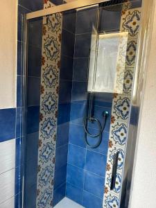 a shower in a bathroom with blue tiles at Correri 125 in Modica