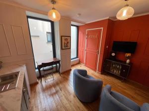 a living room with red walls and a blue chair at Le Rococo f2 climatisé plein centre in Monistrol-sur-Loire