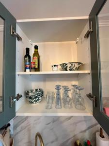 a kitchen pantry with glass bottles and bowls at Le Rococo f2 climatisé plein centre in Monistrol-sur-Loire +8 photos