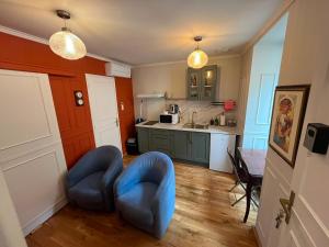 a living room with a blue chair and a kitchen at Le Rococo f2 climatisé plein centre in Monistrol-sur-Loire