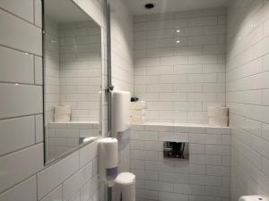 a white tiled bathroom with a toilet and a mirror at Måby Park Hotel Arlanda in Arlanda +28 photos