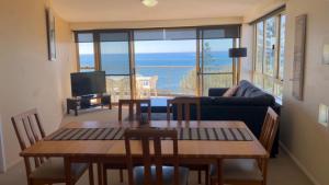 a living room with a couch and a table with chairs at Sea Eagles Unit 9 in Caloundra