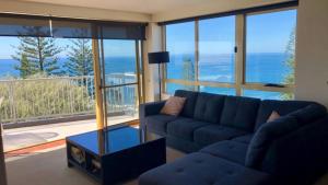 a living room with a blue couch and a large window at Sea Eagles Unit 9 in Caloundra