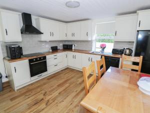 a kitchen with white cabinets and a wooden table at Greenfield House in Aghavas