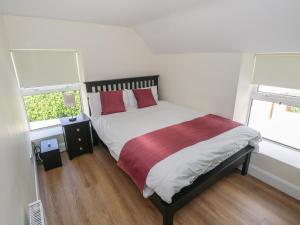 a bedroom with a bed with red pillows and two windows at Greenfield House in Aghavas