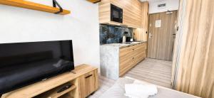 a living room with a large television and a kitchen at Royal Smart Apartments Cracow in Krakow
