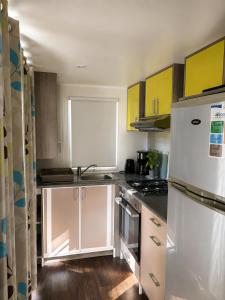 a kitchen with yellow cabinets and a white refrigerator at Le Cocon de Galaure in Châteauneuf-de-Galaure