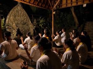 a group of people sitting in front of a stone sculpture at The Campuhan Retreat in Munggu