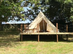 a canvas tent with a chair on a wooden platform at Canutes Field bell tent in Nassington