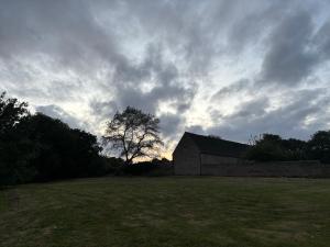 a barn in a field under a cloudy sky at Canutes Field bell tent in Nassington