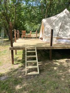 a wooden platform with a tent and a ladder at Canutes Field bell tent in Nassington