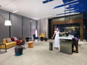 a woman with a suitcase standing in a room at ibis Styles Bangkok Sukhumvit 4 in Bangkok