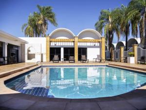 a swimming pool in front of a building with palm trees at ibis Styles Rio Preto Monte Libano in Sao Jose do Rio Preto