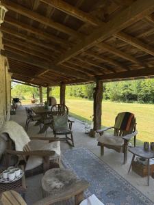 a patio with chairs and tables and a wooden roof at Rimbes Casteljaloux - Gite 6 pers in Casteljaloux