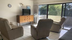 a living room with two chairs and a television at Brighton Le Sands Unit 6 in Golden Beach