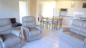 a living room with chairs and a table and a kitchen at Brighton Le Sands Unit 6 in Golden Beach