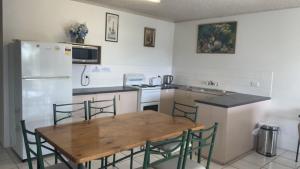 a kitchen with a wooden table and a refrigerator at Brighton Le Sands Unit 6 in Golden Beach