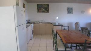 a kitchen with a wooden table and a white refrigerator at Brighton Le Sands Unit 6 in Golden Beach