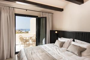 a bedroom with a bed and a balcony with a table at Avento Luxury Suites in Santorini +86 photos