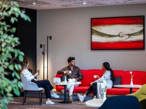 a group of people sitting on a red couch at Ibis Jeddah Malik Road in Jeddah