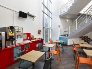 a restaurant with tables and chairs and a staircase at hotelF1 Longwy in Longwy