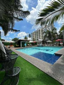 a large swimming pool with green grass and a building at At The Pad Hotel & Villa's in Angeles