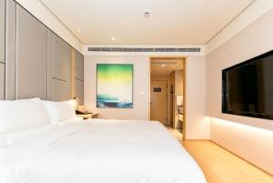 a bedroom with a white bed and a flat screen tv at JI Hotel Shanghai Stadium in Shanghai