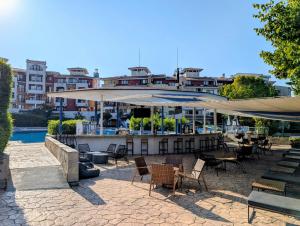a patio with chairs and umbrellas in front of a building at Sea View Holiday for Family and Friends Aheloy, near Sunny Beach-Почивка с изглед към морето за семейство и приятели Ахелой, близо до Слънчев бряг in Aheloy
