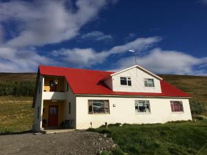 una casa blanca con techo rojo en una colina en Öndólfsstaðir Farm B&B en Laugar