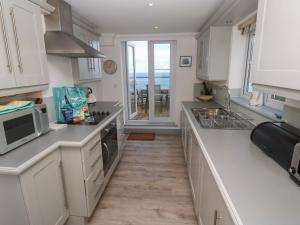 a kitchen with white cabinets and a view of the ocean at Ocean Gem in Carbis Bay