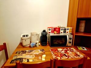 a wooden table with a microwave and a table with a table at Bernina Stop & Go apartment - 30 steps to the red train in Tirano