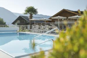 a swimming pool with chairs and umbrellas at Hotel Garni Paler in Tirolo