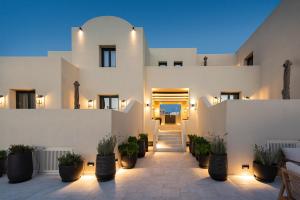 a white building with potted plants in a courtyard at Avento Luxury Suites in Santorini
