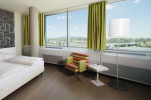 a bedroom with a bed and a chair and a window at harry's home Wien hotel & apartments in Vienna
