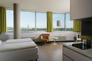 a room with a bed and a chair and windows at harry's home Wien hotel & apartments in Vienna