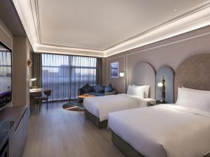 a hotel room with two beds and a couch at Mercure Beijing Zhongguancun in Beijing