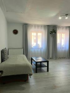 a bedroom with a bed and a table and windows at La Cascata in Valbrenta 
