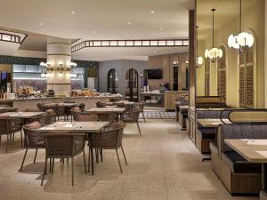 a restaurant with tables and chairs and a kitchen at Mercure Bengkulu in Bengkulu
