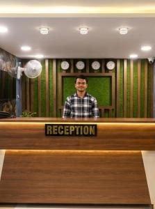a man is standing behind a reception desk at Hotel Sky Palace Airport Zone in Hyderabad