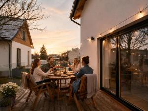 a group of people sitting around a table on a patio at Wellness Apartmány Vila Republika in Velké Losiny