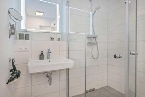 a white bathroom with a sink and a shower at An der Haffküste Haffkoje in Zirchow +30 photos