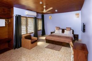 a bedroom with a bed and a chair at Aniyak Guest House in Sekondi-Takoradi