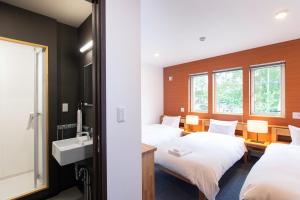 a hotel room with two beds and a sink at Hirafu Tomten in Kutchan