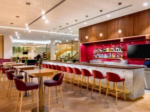a bar with red chairs and tables in a restaurant at MÖVENPICK Hotel Stuttgart Messe & Congress in Stuttgart