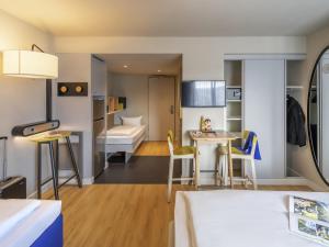 a small room with a bed and a small table and chairs at Aparthotel Adagio Access Freiburg in Freiburg im Breisgau