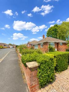 a brick house with hedges in front of a street at Westfields Bungalow in Mirfield