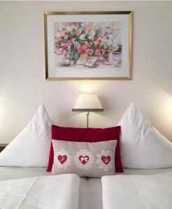 a bedroom with a bed with red pillows and a painting at Hotel-Café Residenz Bad Bertrich in Bad Bertrich